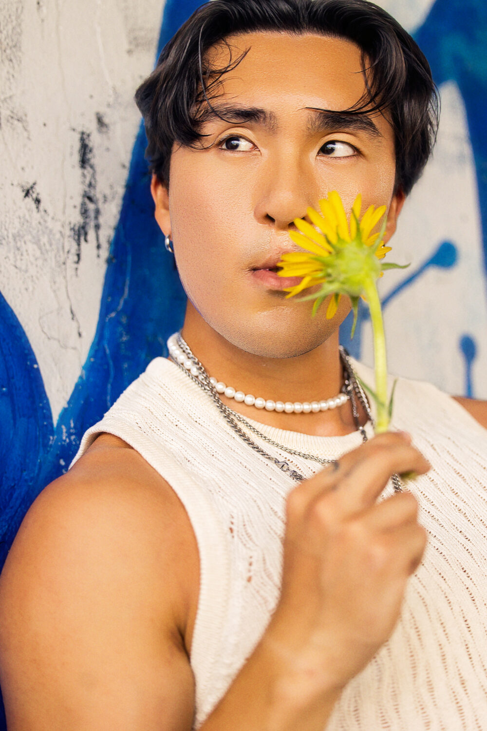 Editorial portrait with sunflower, blue mural backdrop